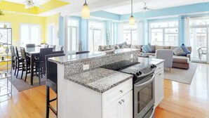 Una cocina luminosa con encimeras de granito, estufa y un comedor con sillas y mesa.