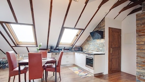 A kitchen with skylights, wooden beams, a brick backsplash, and a dining area with chairs. - Apartment "Haus Elena Wohnung 7A" with Mountain View, A/C, Wi-Fi, Garden & Terrace (Bestwig)