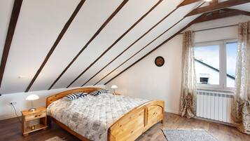 A bedroom with a wooden bed, a nightstand with a lamp, a radiator, and a window with curtains.