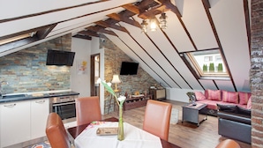 An attic room with a kitchen, dining area, and seating. - Apartment "Haus Elena Wohnung 7A" with Mountain View, A/C, Wi-Fi, Garden & Terrace (Bestwig)