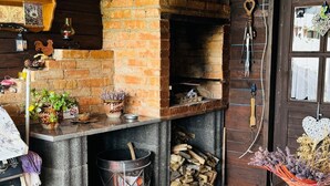 A rustic kitchen with a brick oven, wooden shelves, and a table with a floral tablecloth. - Apartment "Haus Elena Wohnung 7A" with Mountain View, A/C, Wi-Fi, Garden & Terrace (Bestwig)