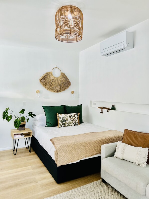 Un dormitorio moderno con cama, mesita de noche y lámpara colgante.