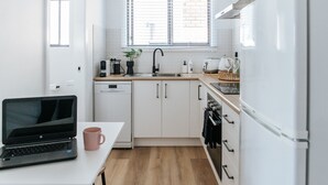 A modern kitchen with white cabinets, a wooden countertop, a sink, a dishwasher, a stove, and a refrigerator. - Studio On Lewis Luxury Tiny House 4 mins to town (Mudgee)