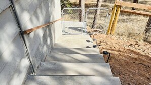 A concrete staircase leading to a fenced area with a wooden post and metal gates.