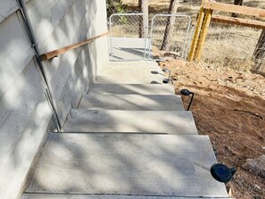 A concrete staircase leading to a fenced area with a wooden post and metal gates.