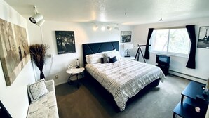 A bedroom with a large bed, bedside tables, a desk, and a chair.