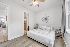 A bedroom with a large bed, a ceiling fan, a bedside table with a lamp, and a wall art piece. - Unwind Your Mind...5 BR,4.5 baths...Book now for Summer (Panama City Beach)