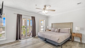 A bedroom with a bed, a nightstand, a ceiling fan, and large windows. - Unwind Your Mind...5 BR,4.5 baths...Book now for Summer (Panama City Beach)