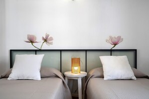 A hotel room with two beds, a nightstand with a lamp, and wall-mounted floral decorations.