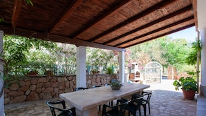Une terrasse extérieure avec un sol en pierre, une table en bois et des chaises.