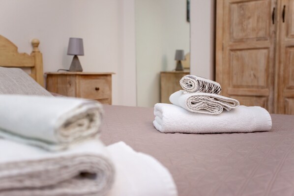 En snyggt bäddad säng med hoprullade handdukar och en sänggavel i trä.