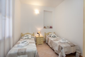 Une chambre avec deux lits, une table de chevet avec une lampe, un miroir et une étagère avec des objets décoratifs.