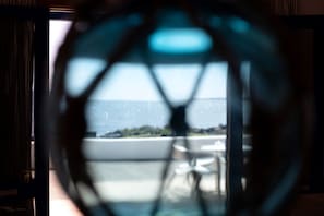 A view through a window with a geometric pattern, a pool, and a distant landscape.