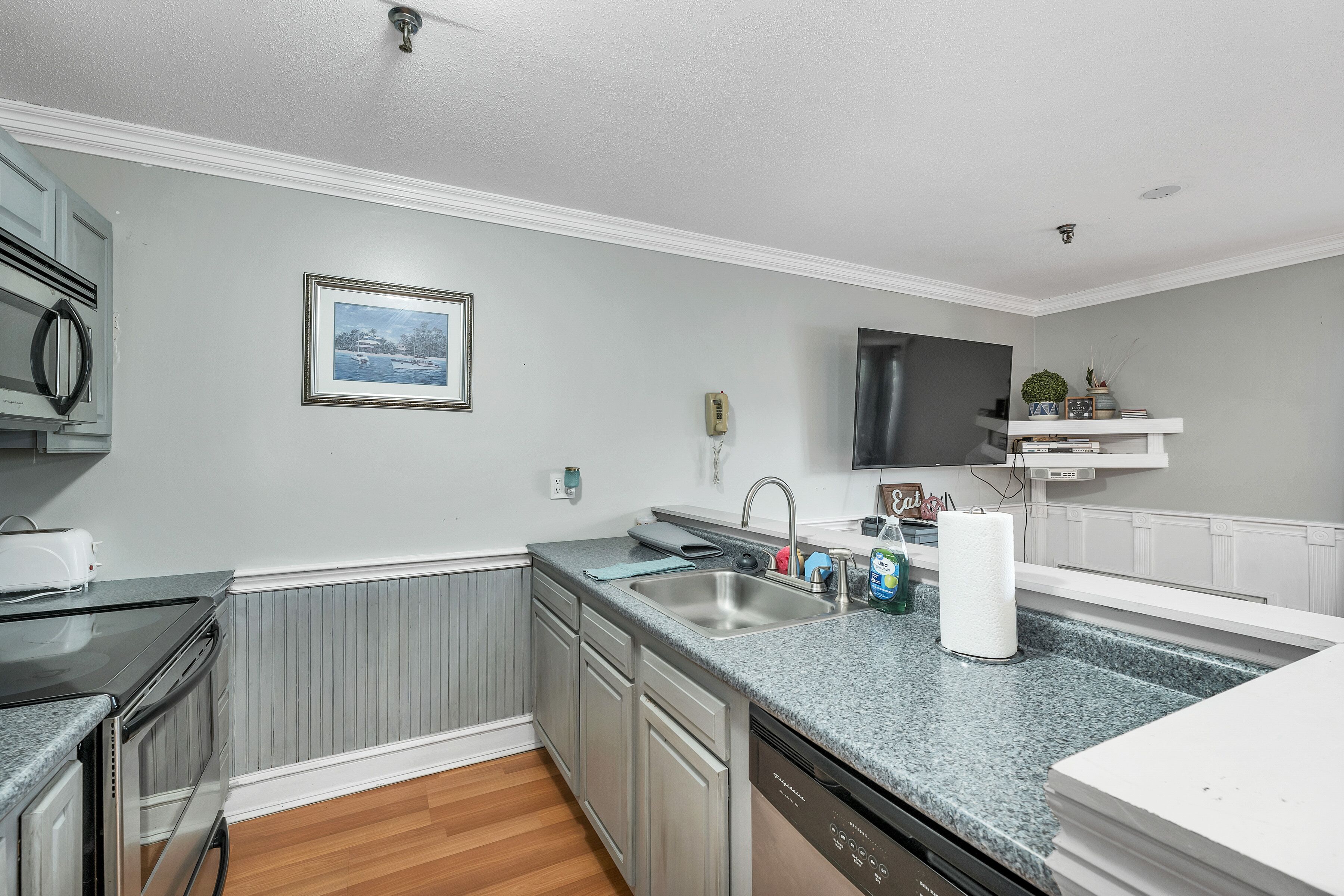 A modern kitchen with a granite countertop, stainless steel sink, and built-in dishwasher.