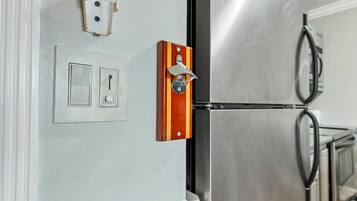 Eine Küche mit einem Edelstahlkühlschrank, einem Holzgriffen und einem an der Wand montierten Lichtschalter.