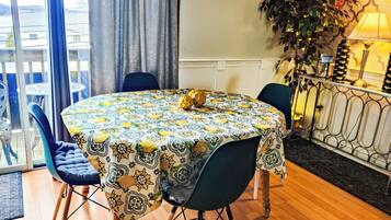 A round table with a patterned tablecloth, surrounded by chairs, in a room with a balcony view.