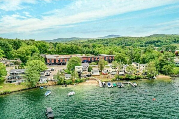 Stunning lakeside homes surround a charming red brick building amidst lush greenery and a serene lake.