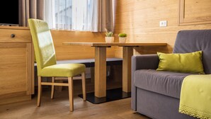 Una habitación con un escritorio de madera, una silla verde, un sofá gris y una almohada verde, además de un televisor.