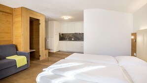 Una habitación con cama, sofá, pared de madera y zona de cocina.
