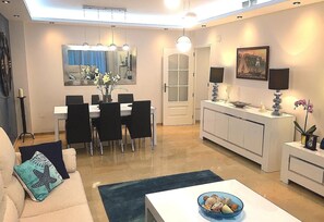 Ein modernes Wohnzimmer mit Essbereich, einem weißen Sofa, einem Couchtisch und einem Esstisch mit Stühlen.