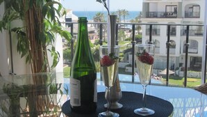 Un balcone con un tavolo, una bottiglia verde e due flute da champagne con fragole.
