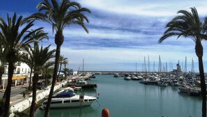 Una marina con imbarcazioni ormeggiate, palme e cielo sereno.