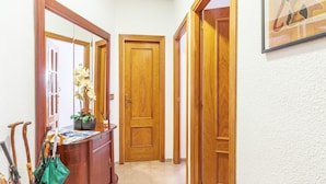 A hallway with wooden doors, a wooden bench with umbrellas, and a framed artwork on the wall. - Holiday Apartment in Alicante with Air Conditioning & WiFi (Alicante)