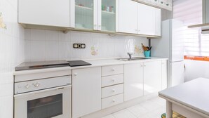 A kitchen with white cabinets, a stove, and a sink. - Holiday Apartment in Alicante with Air Conditioning & WiFi (Alicante)