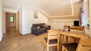 Una cocina moderna con comedor, suelo de madera y un sofá gris.