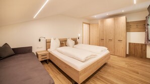 Un dormitorio con cama, mesitas de noche, armario y mesilla.