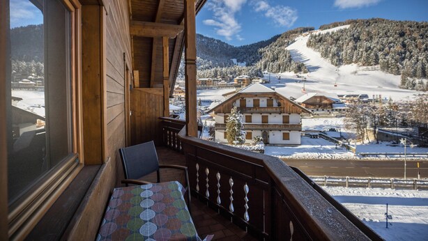Ein Holzbalkon mit Blick auf einen schneebedeckten Berg und ein Skigebiet.