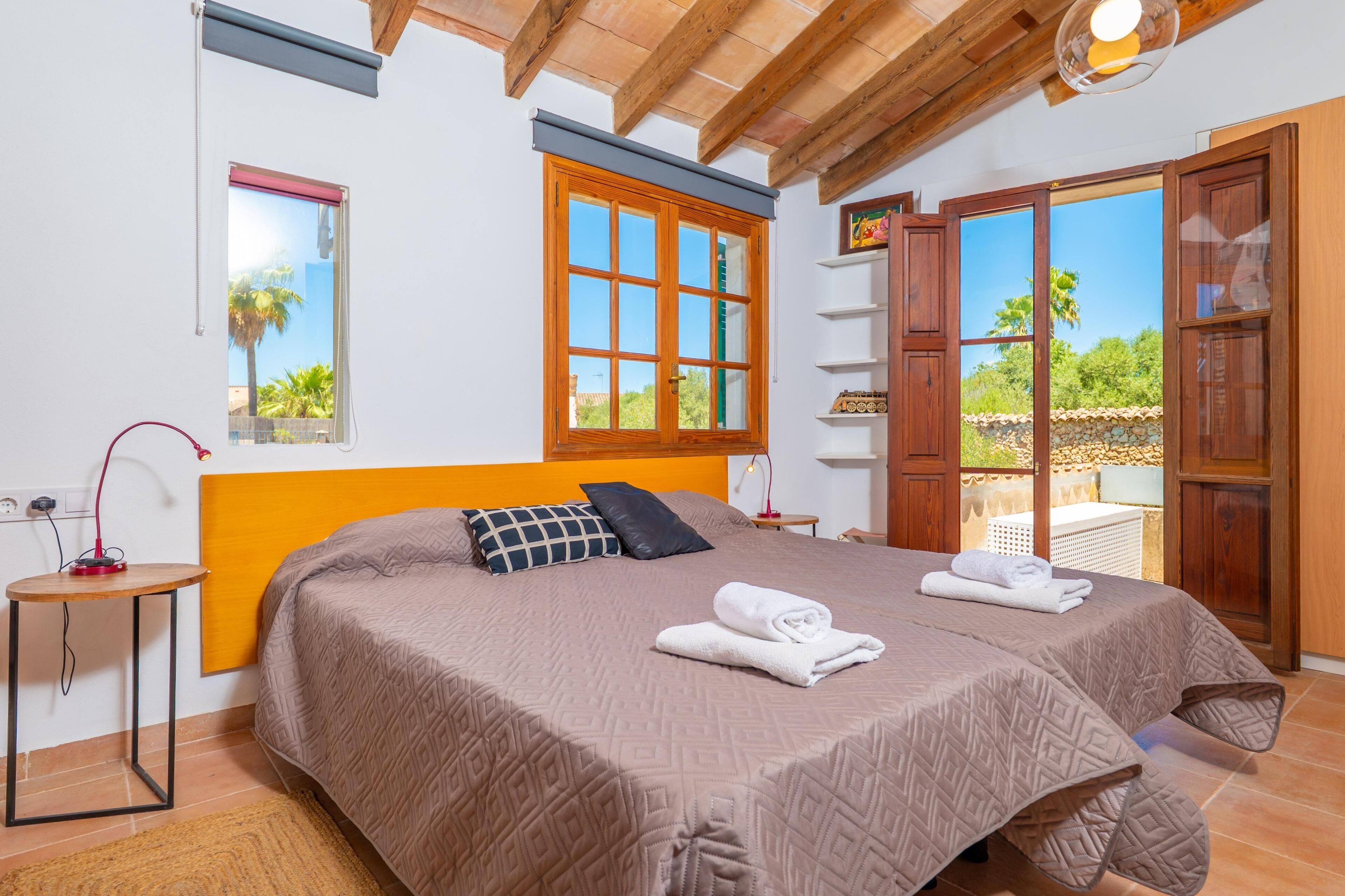 A bedroom with a bed, a window, a shelf, and a door.