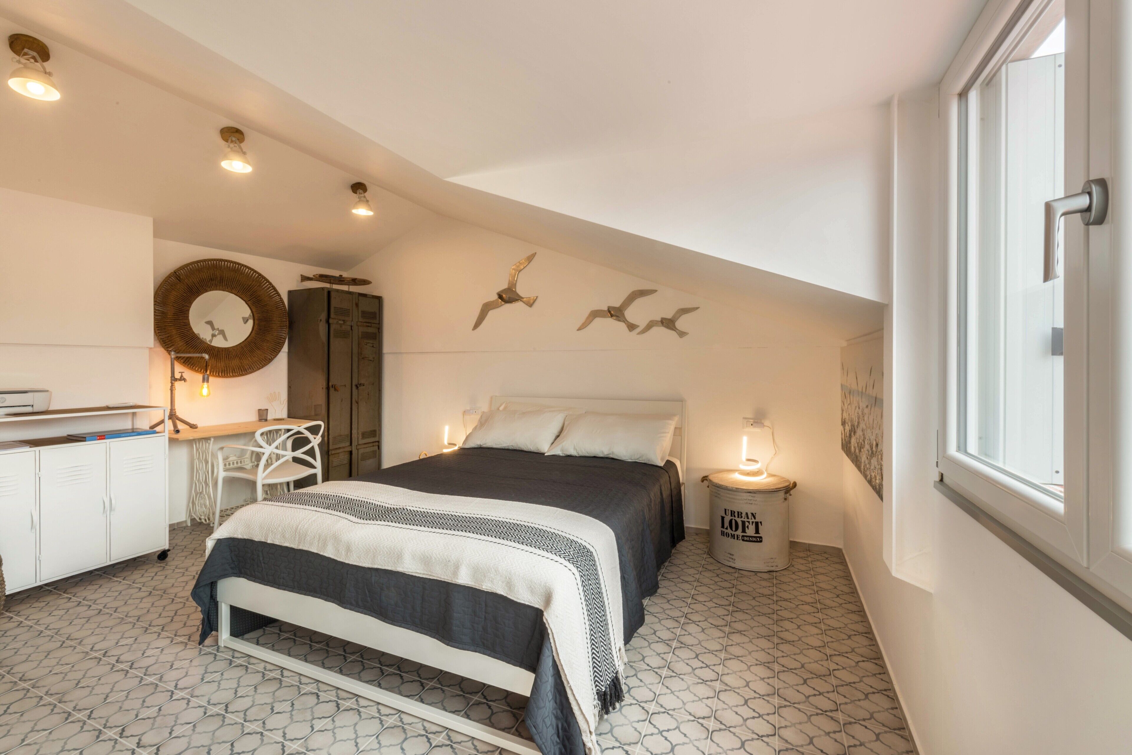 Een slaapkamer met een bed, nachtkastje, lamp, kledingkast, bureau, stoel en een raam.