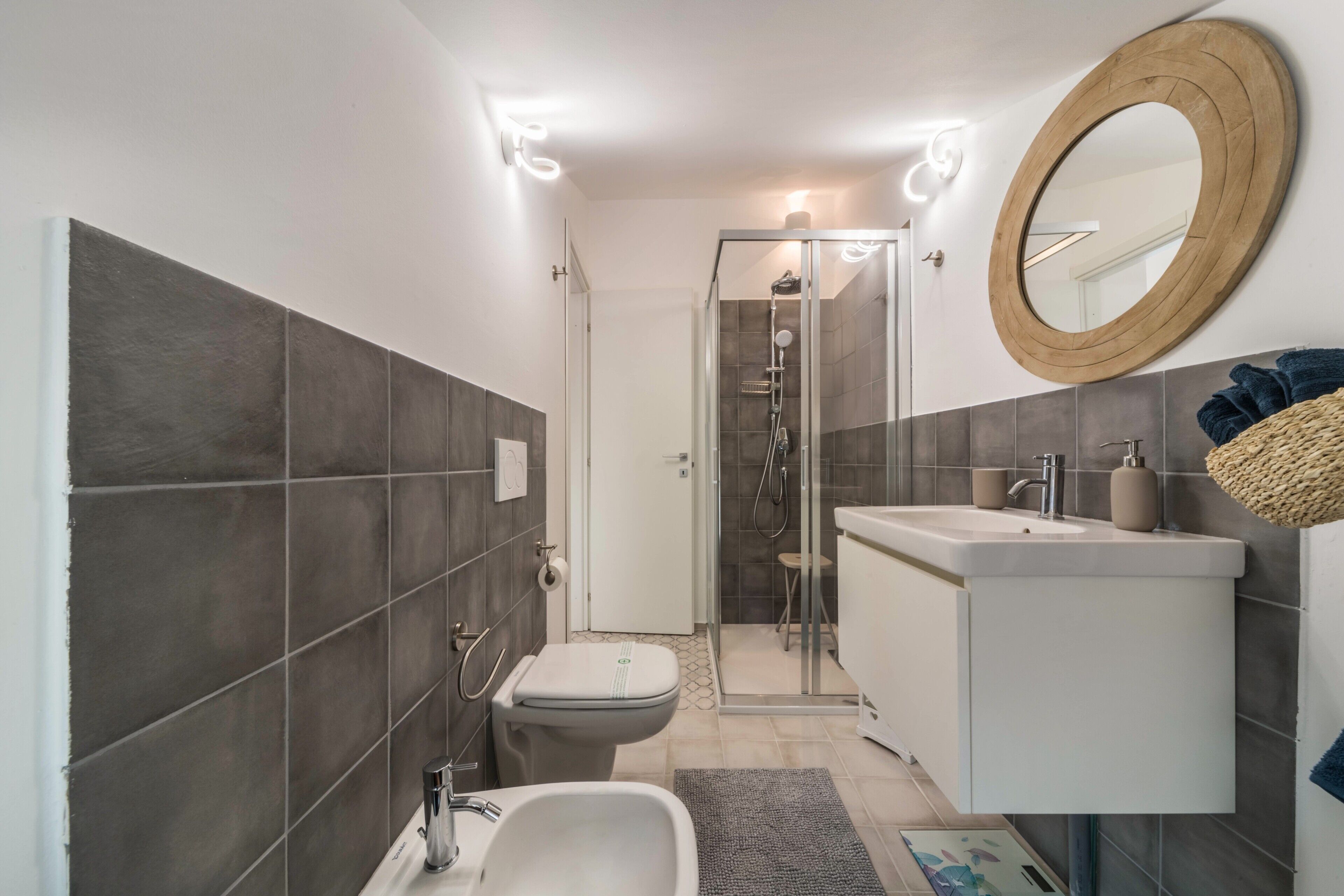 Ein modernes Badezimmer mit Dusche, Toilette, Waschbecken und einem großen Spiegel.
