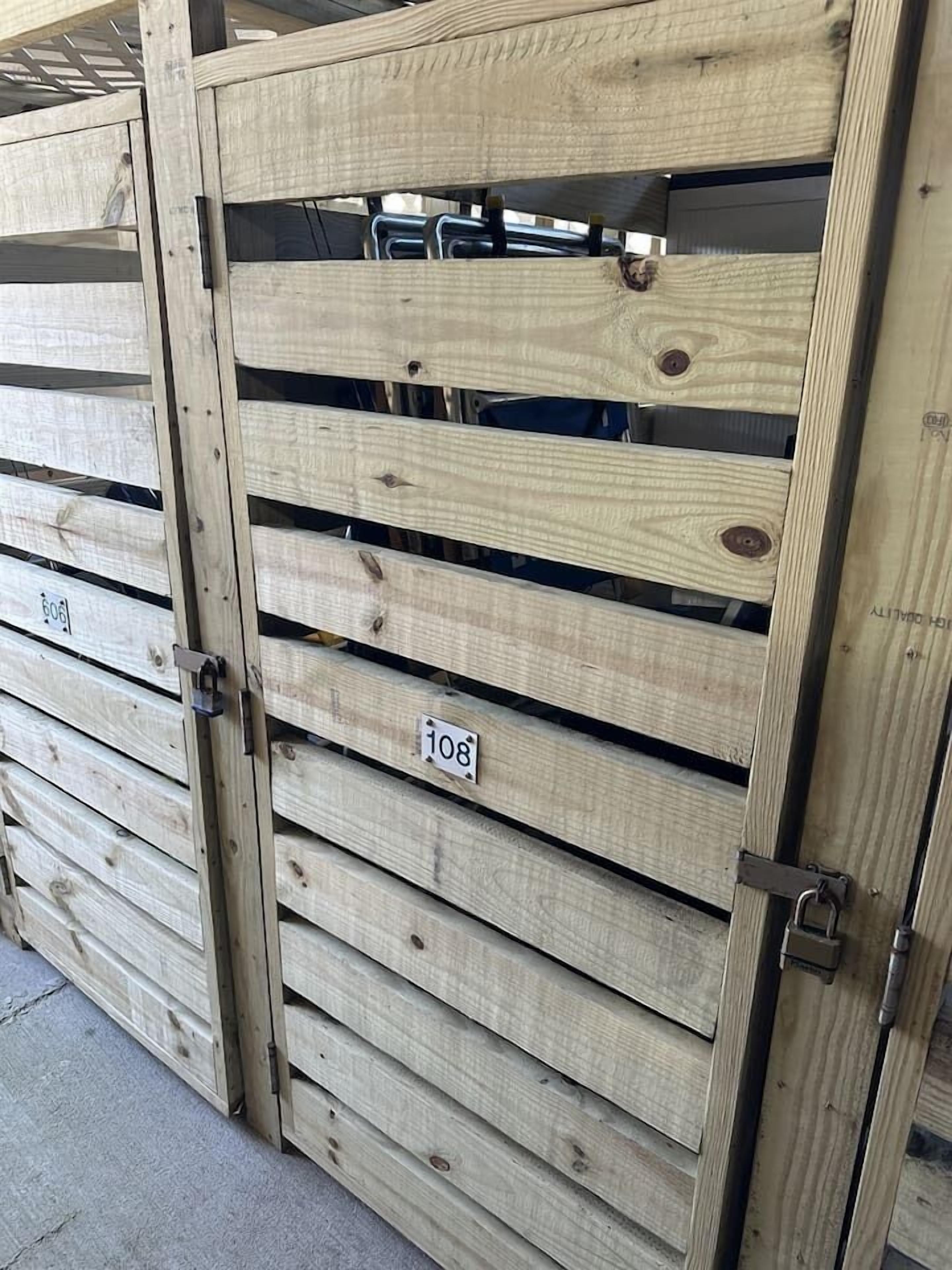 A stack of wooden doors with metal latches and numbered labels.