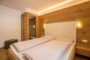 A modern bedroom with two beds, wooden paneling, and built-in lighting.