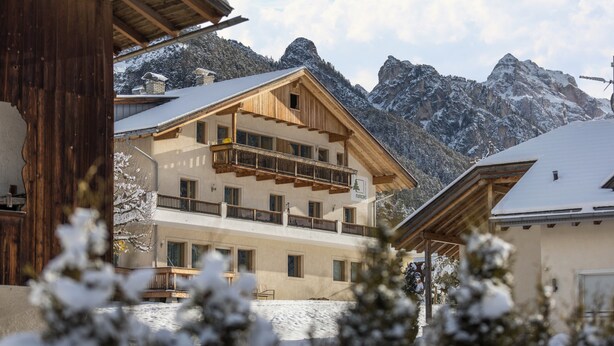 A multi-story building with balconies, a wooden facade, and a mountainous backdrop. - Holiday Apartment "Runcac Plaies" with Mountain View, Wi-Fi & Balcony (San Vigilio)