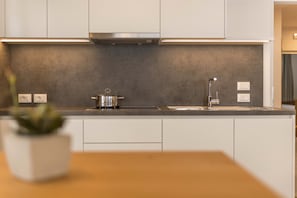 Une cuisine moderne avec des armoires blanches, une hotte de cuisinière en acier inoxydable, un évier et un plan de travail.