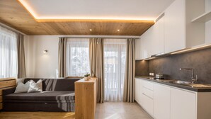 A modern kitchen with a wooden ceiling, a built-in island, and a large window with curtains. - Holiday Apartment "Runcac Plaies" with Mountain View, Wi-Fi & Balcony (San Vigilio)
