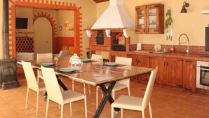 A kitchen with a brick oven, wooden cabinets, and a dining area with a glass table and chairs.
