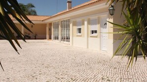 A building with a tiled roof, large windows, and a paved courtyard.