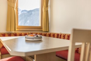 A table with a woven basket containing oranges, a window with a mountain view, and red cushioned seating.