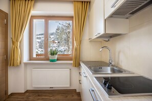 A kitchen with a window, a radiator, a sink, and a stove.