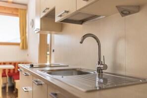 A modern kitchen with stainless steel appliances, a double sink, and a window with curtains.