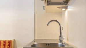 Eine Küche mit einem Edelstahl-Spülbecken, einem modernen Wasserhahn und einer hellen Arbeitsplatte.