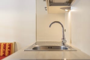Eine Küche mit einem Edelstahl-Spülbecken, einem modernen Wasserhahn und einer hellen Arbeitsplatte.
