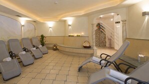 Ein Wellnessbereich mit Liegestühlen, einer Rezeption und einem steinernen Bogen.