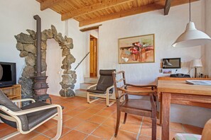 A rustic interior with a stone archway, a fireplace, a wooden ceiling, a dining table, and a television. - Holiday Home Casa Caldereta with Mountain View, Pool, Wi-Fi & Terrace (Guatiza)