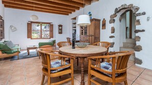 A dining area with a round wooden table, chairs, and a hanging light fixture. - Holiday Home Casa Cueva with Mountain View, Pool, Wi-Fi & Terrace (Guatiza)