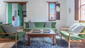 A living room with a green sofa set, a wooden coffee table, and a view of the outside. - Holiday Home Casa Cueva with Mountain View, Pool, Wi-Fi & Terrace (Guatiza)